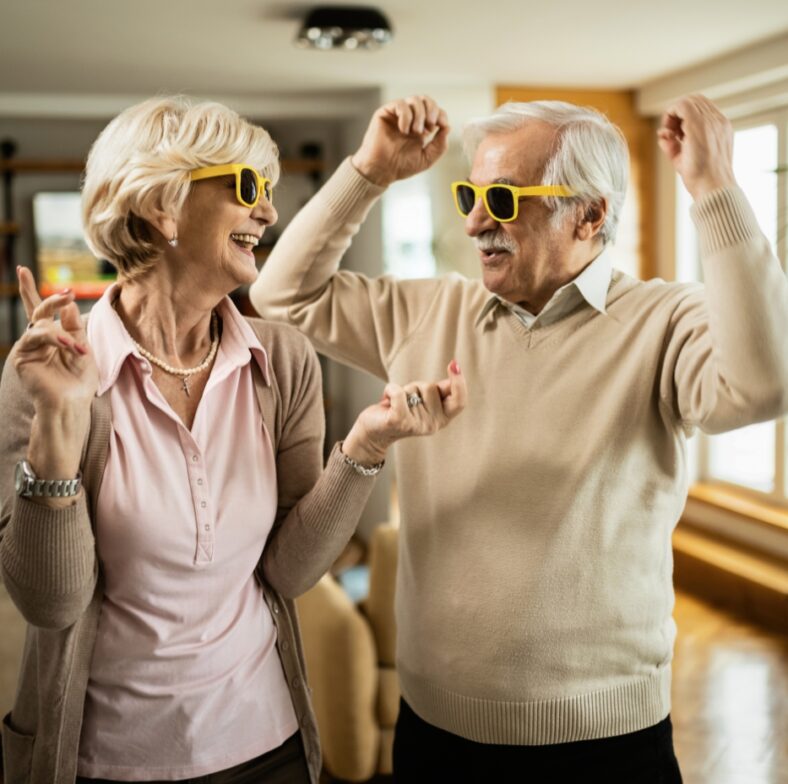 Rozbawieni tańczący seniorzy w okularach przeciwsłonecznych